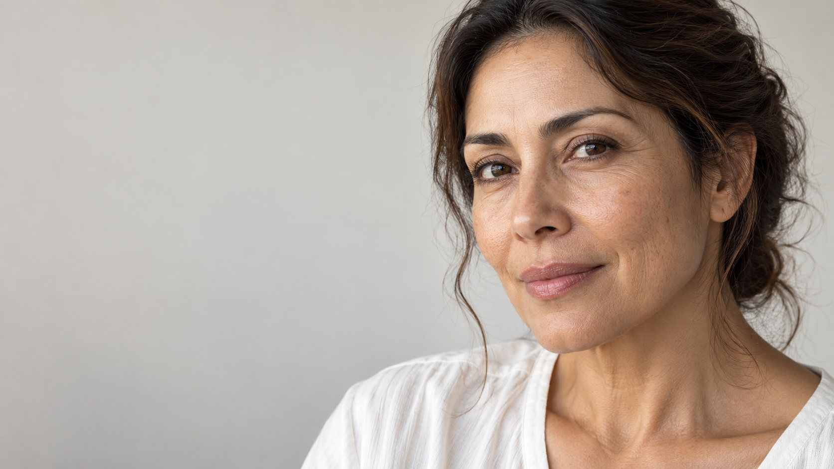 Mujer de piel de tono medio, con textura natural y líneas finas visibles.